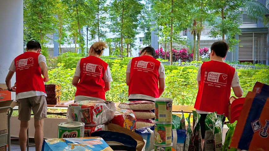 volunteers wearing the iconic red food from the heart vest packing donations at a food drive